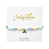 Beaded bracelet with a gold whale tail charm on a 'California' branded card.