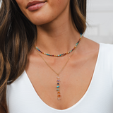 Close-up of a woman wearing a colorful beaded necklace with a white top.