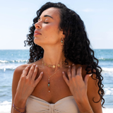 Woman on a beach wearing jewelry with ocean in the background