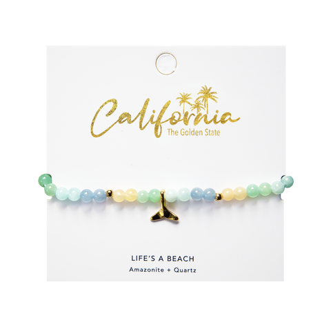 Beaded bracelet with a gold whale tail charm on a 'California' branded card.