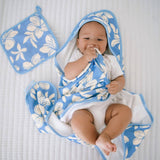 Baby wrapped in a blue and white floral hooded towel on a white background