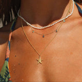 Close-up of a person wearing a gold starfish necklace