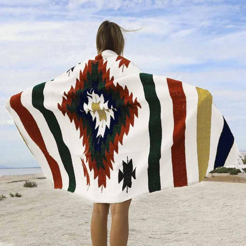 Person wearing a colorful patterned blanket in a desert setting