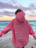Person wearing a pink hoodie with a beach and sunset in the background